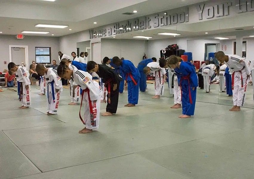 Children bowing respectfully at the start of a traditional martial arts session.