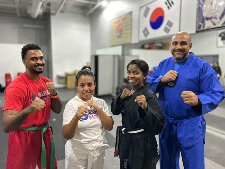 Adult students posing confidently in martial arts uniforms inside a professional training dojo.