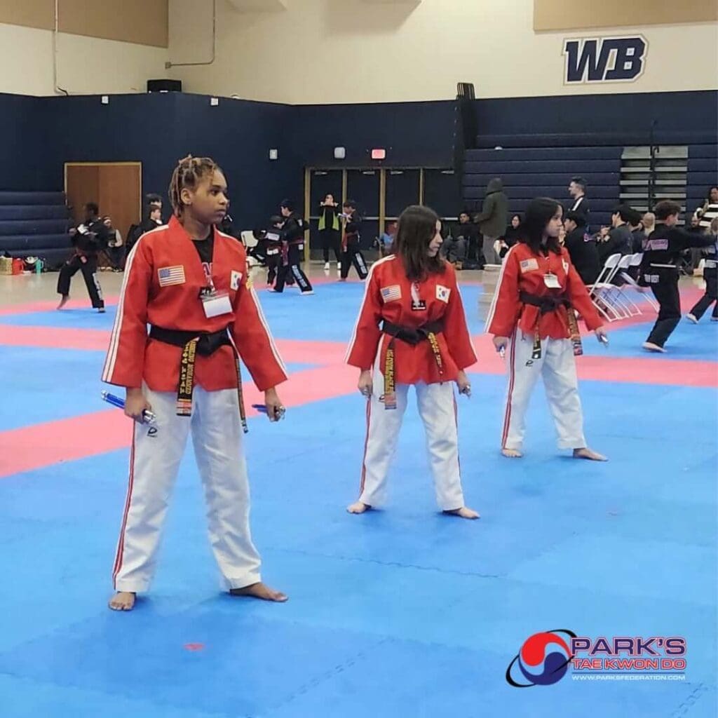 Young Taekwondo students standing in formation during a martial arts competition, demonstrating their developing skills and martial arts progression.