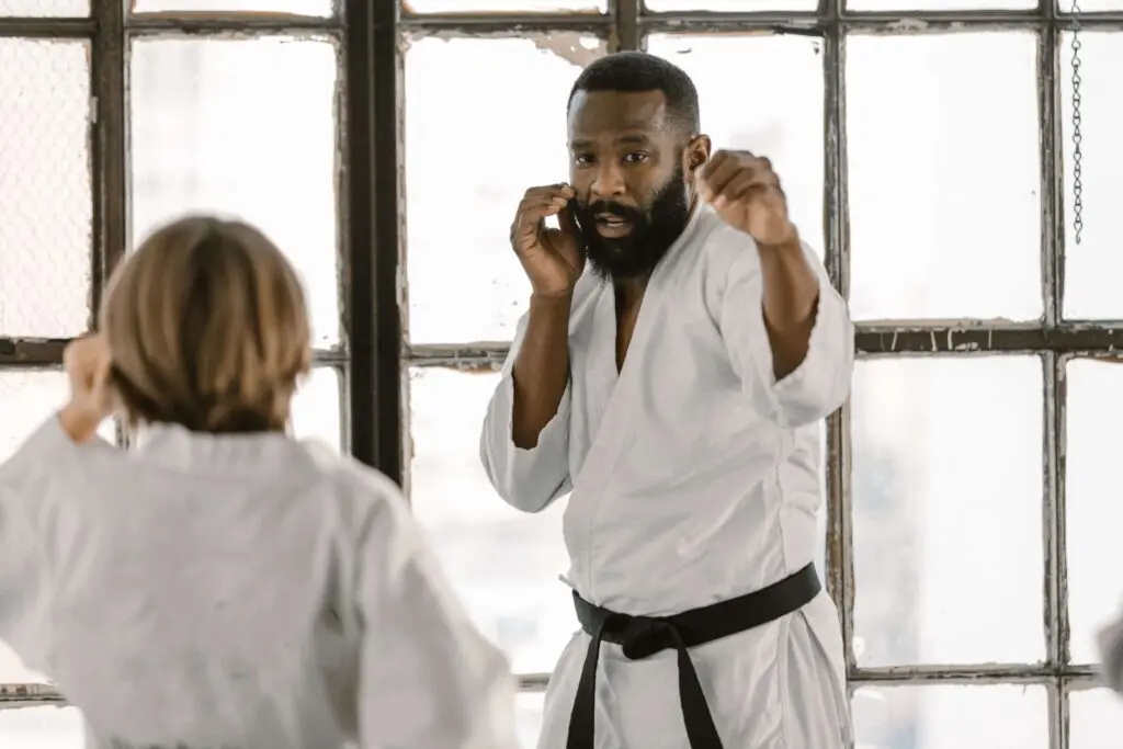 Martial arts student practicing a guarded stance and preparing a strike with a partner during a beginner combat training session, situational awareness for self defense.