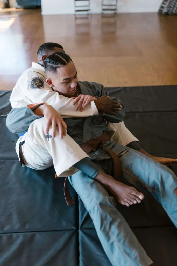 Brazilian Jiu Jitsu students practising a grappling control technique on the mat during beginner martial arts training focused on reading movement and awareness, situational awareness for self defense.