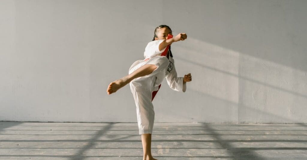 Young martial arts student performing a controlled high kick while practicing taekwondo technique fundamentals for beginners.