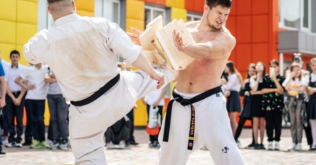 Martial artist breaking wooden boards with a powerful kick while demonstrating skills built from taekwondo technique fundamentals for beginners.