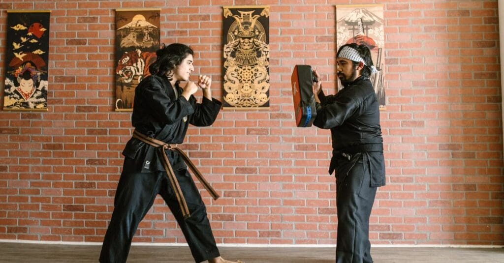 Martial arts student practicing punches with an instructor holding a focus pad during taekwondo technique fundamentals for beginners.