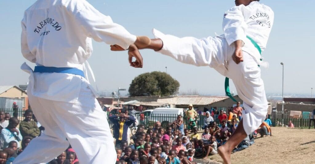 Two martial arts students practicing controlled kicking techniques outdoors while demonstrating taekwondo technique fundamentals for beginners.